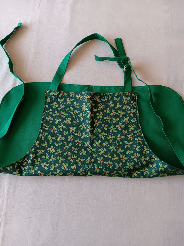 Childs Kitchen Play Apron Green Holly Patterned Cotton Fabric with Front pocket and Green lining, waist ties and adjustable neck ties 