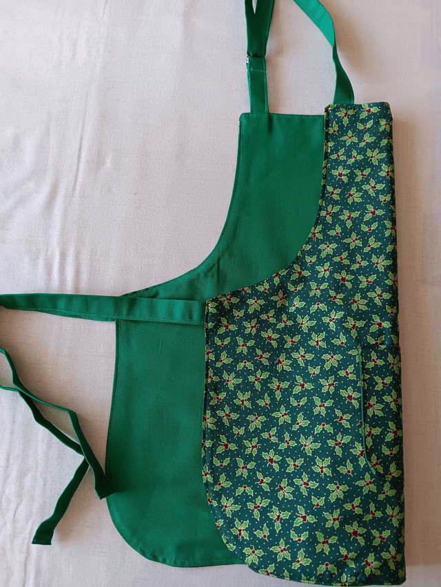 Childs Kitchen Play Apron Green Holly Patterned Cotton Fabric with Front pocket and Green lining, waist ties and adjustable neck ties 