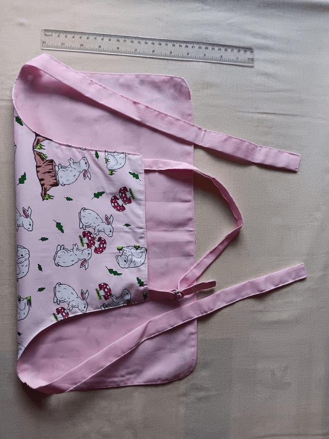 Childs Kitchen Play Apron Pink Bunnies Patterned Cotton Fabric with Front pocket and pink lining, waist ties and adjustable neck ties 