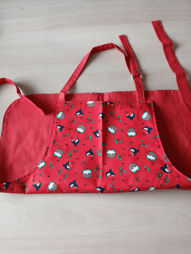 Childs Kitchen Play Apron Pudding Patterned Cotton Fabric with Front pocket and Red lining, waist ties and adjustable neck ties (1)