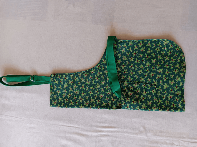 Childs Kitchen Play Apron Green Holly Patterned Cotton Fabric with Front pocket and Green lining, waist ties and adjustable neck ties 
