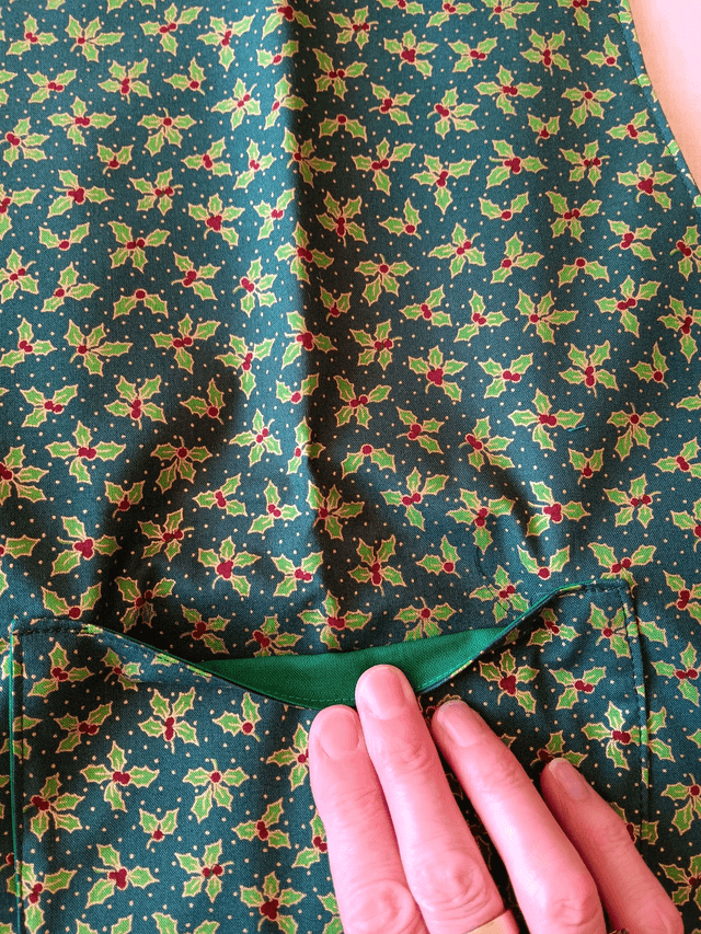 Childs Kitchen Play Apron Green Holly Patterned Cotton Fabric with Front pocket and Green lining, waist ties and adjustable neck ties 