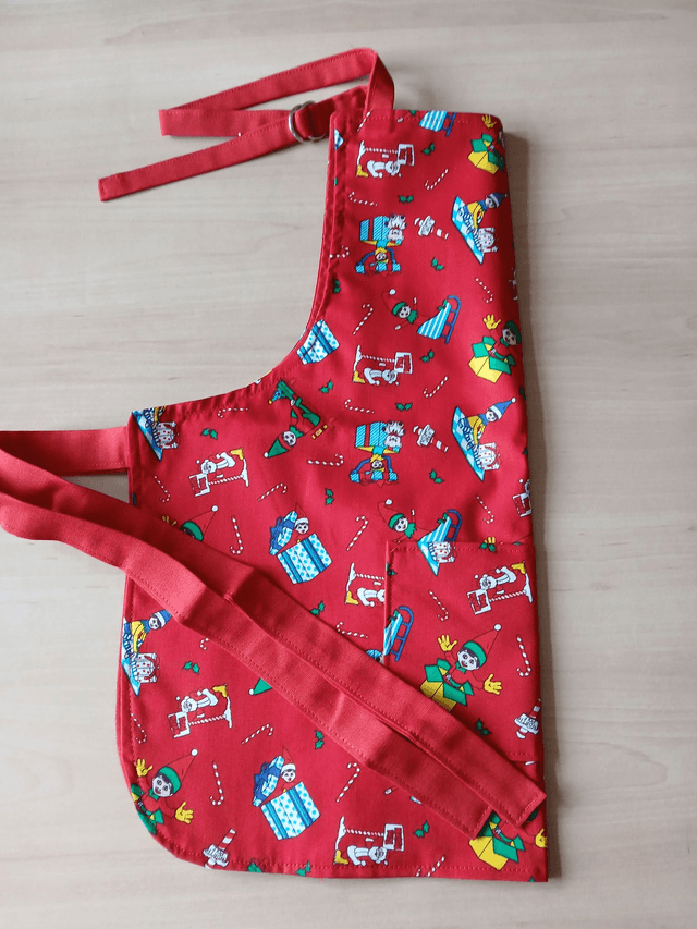 Childs Kitchen Play Apron Festive Patterned Cotton Fabric with Front pocket and Red lining, waist ties and adjustable neck ties