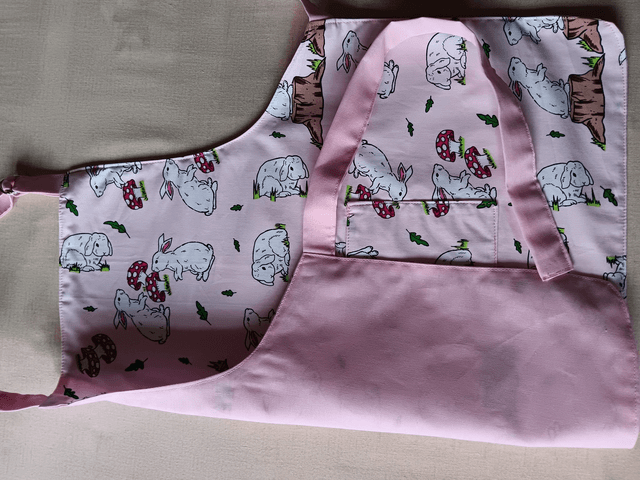 Childs Kitchen Play Apron Pink Bunnies Patterned Cotton Fabric with Front pocket and pink lining, waist ties and adjustable neck ties 