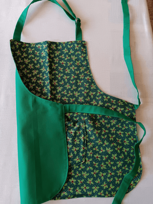 Childs Kitchen Play Apron Green Holly Patterned Cotton Fabric with Front pocket and Green lining, waist ties and adjustable neck ties 