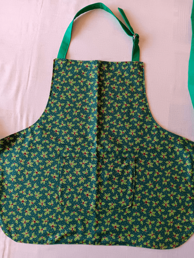 Childs Kitchen Play Apron Green Holly Patterned Cotton Fabric with Front pocket and Green lining, waist ties and adjustable neck ties 